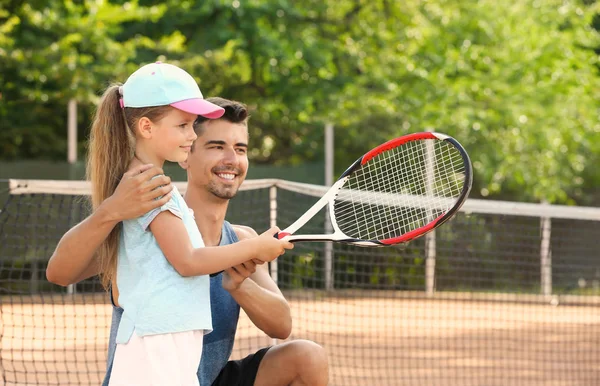 Young trainer with little girl on tennis court — Stock Photo, Image