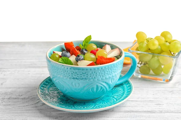 Cup with delicious fruit salad on wooden table — Stock Photo, Image