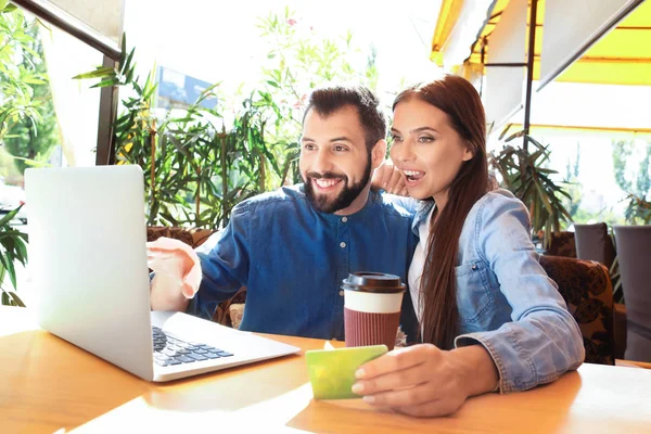 Pasangan muda dengan laptop dan kartu kredit di kafe. Konsep belanja internet — Stok Foto