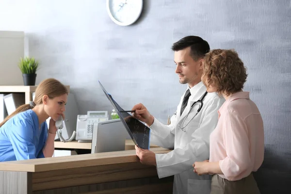 Receptionist and doctor with client in hospital — Stock Photo, Image