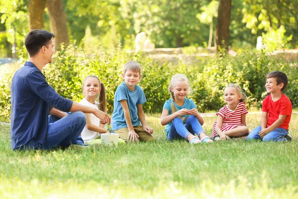 Grupo de crianças com professor no parque no dia ensolarado — Fotografia de Stock
