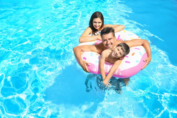 Jovem casal e bonito filho com anel inflável na piscina — Fotografia de Stock