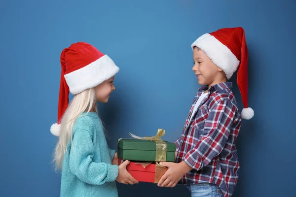 Χαριτωμένα μικρά παιδιά με χριστουγεννιάτικα δώρα από το χρώμα φόντου — Φωτογραφία Αρχείου