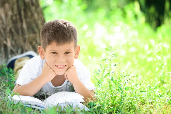 Милий маленький хлопчик читає книгу в парку — стокове фото