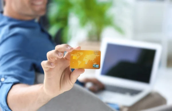 Hombre con portátil con tarjeta de crédito en el interior —  Fotos de Stock