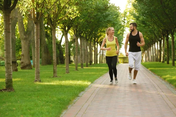 Jeune couple sportif courant dans un parc verdoyant — Photo