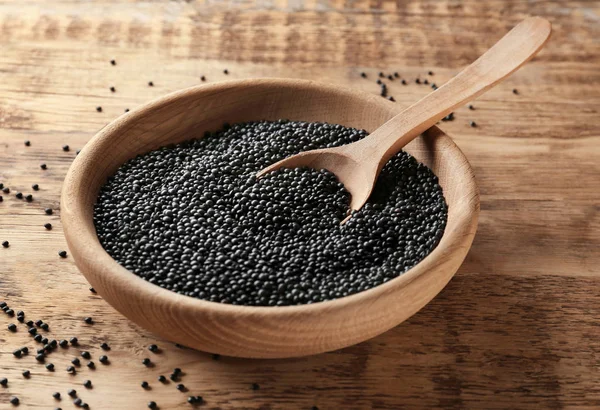 Bowl with black lentils and spoon on wooden background — Stock Photo, Image