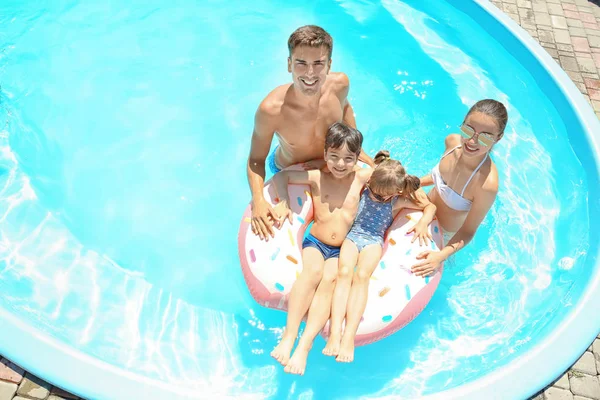 Happy family with inflatable donut in swimming pool — Stock Photo, Image