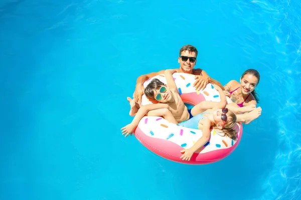 Familia feliz con donut inflable en la piscina — Foto de Stock