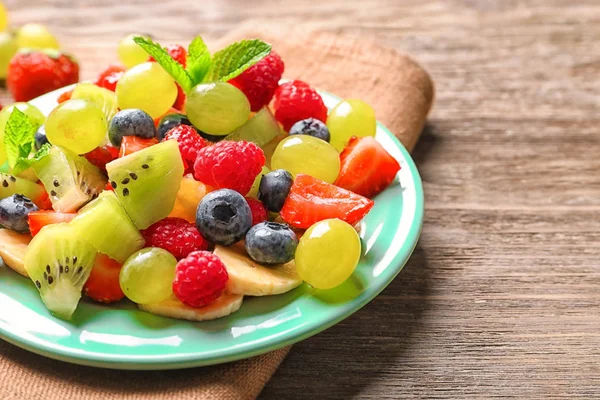 Placa con ensalada de frutas sobre mesa de madera — Foto de Stock