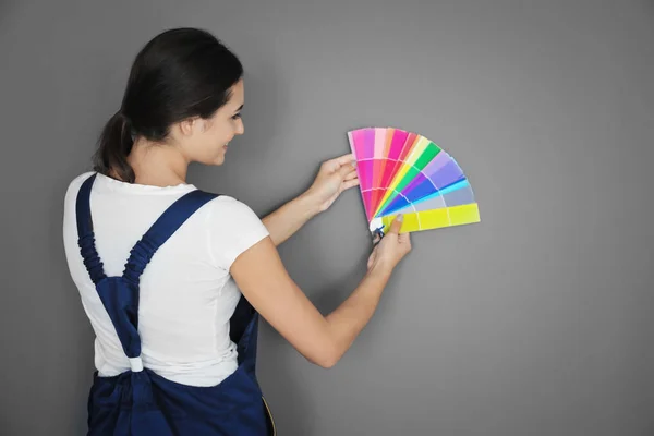 Decorador femenino sosteniendo muestras de paleta de colores sobre fondo gris —  Fotos de Stock