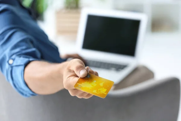 Mann mit Laptop hält Kreditkarte im Haus — Stockfoto