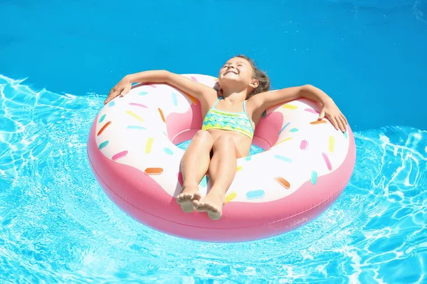 Söt flicka på uppblåsbar ring i poolen — Stockfoto