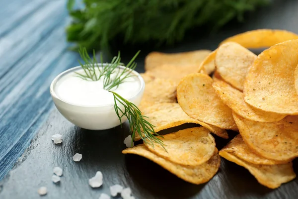 Patatas fritas y crema agria en tazón en plato de pizarra — Foto de Stock