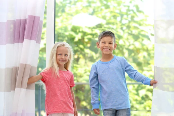 Lindos niños pequeños abriendo cortinas en casa — Foto de Stock