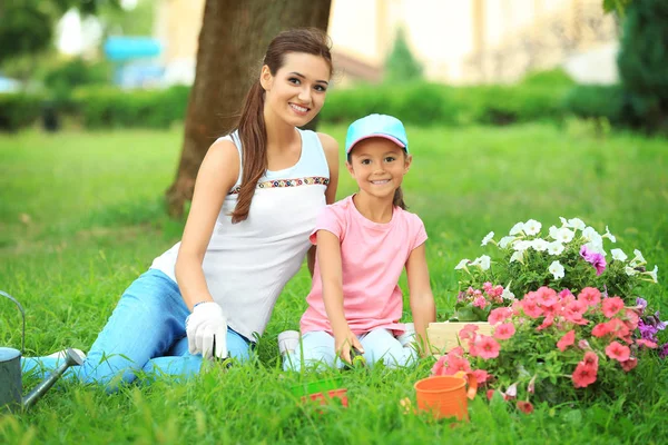 Linda niña con madre plantando flores en el jardín en el día soleado — Foto de Stock