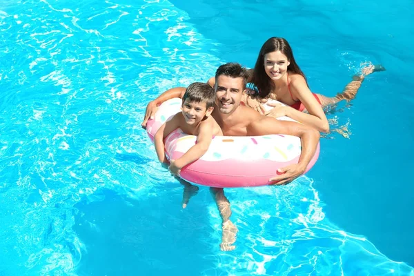 年轻夫妇和可爱的儿子在水池充气的圆环 — 图库照片