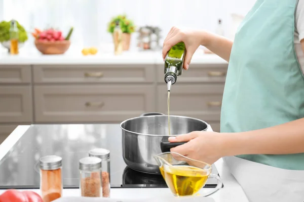 Mulher derramando óleo de cozinha de garrafa — Fotografia de Stock