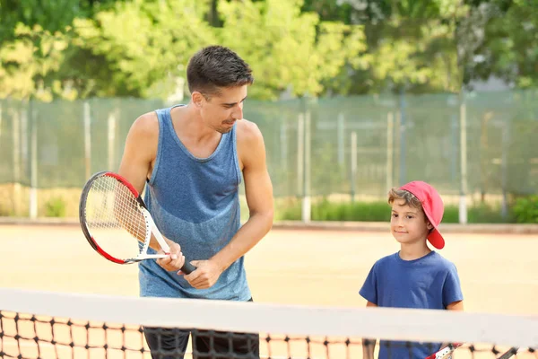 テニスコートで男の子と若いトレーナー — ストック写真