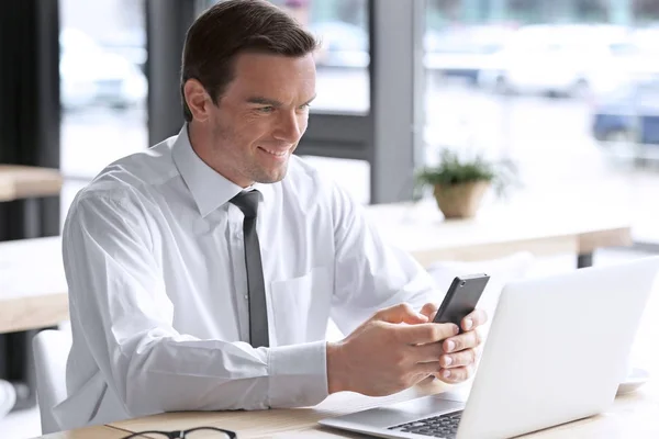 Jeune homme d'affaires utilisant un smartphone sur le lieu de travail — Photo