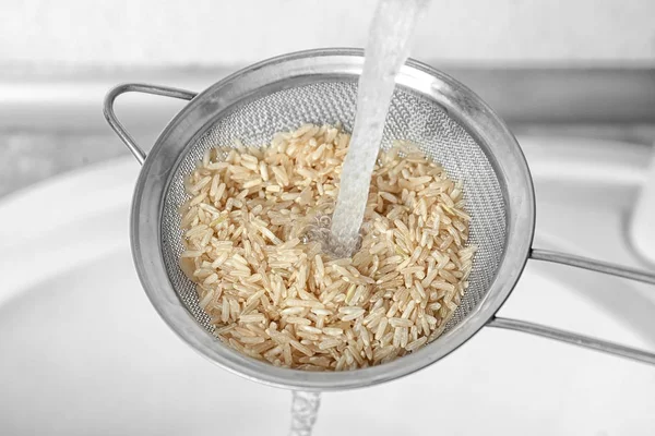 Мойка сырого риса с водой на кухне — стоковое фото