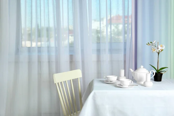 Mesa de serviço perto da janela com cortinas modernas no quarto — Fotografia de Stock