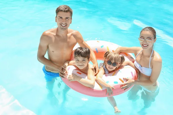 Lycklig familj med uppblåsbara donut i poolen — Stockfoto