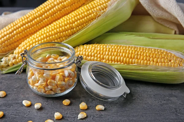 Mazorcas de maíz y frasco de vidrio con granos —  Fotos de Stock