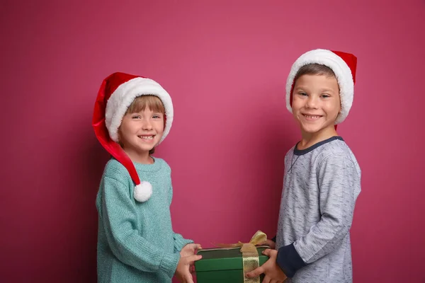 Χαριτωμένα παιδάκια με Χριστουγεννιάτικο δώρο σε χρώμα φόντου — Φωτογραφία Αρχείου