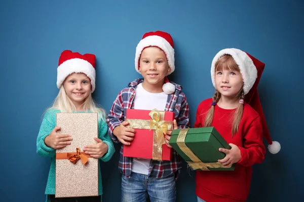 逗人喜爱的孩子与圣诞节礼物在颜色背景 — 图库照片