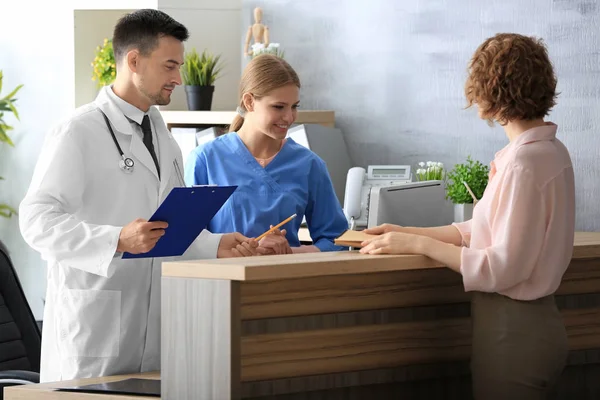 Recepcionista e médico com cliente no hospital — Fotografia de Stock