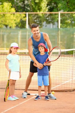 Tenis kortunda Küçük çocuklu genç eğitmeni