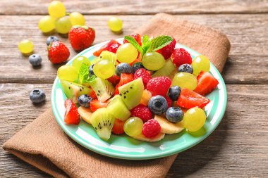 Plaka üzerinde ahşap masa meyve salatası ile