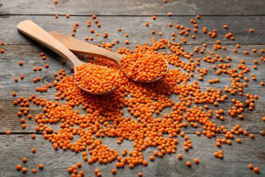 Ahşap masa üzerinde kırmızı mercimek ile kaşık