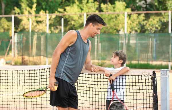 Tenis kortunda küçük çocuk ile genç eğitmeni