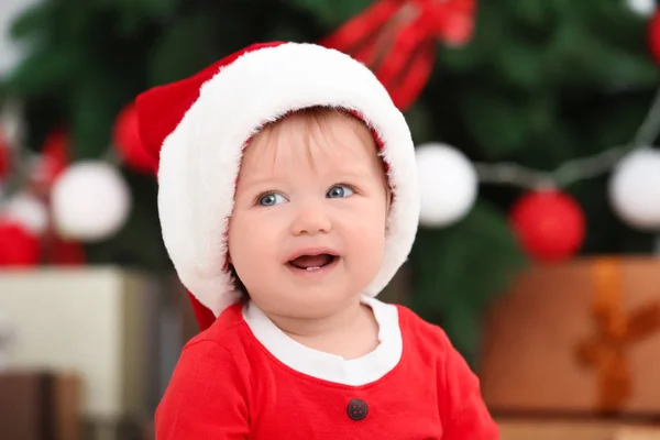 Söt baby i Santa hat mot suddig jul bakgrund — Stockfoto