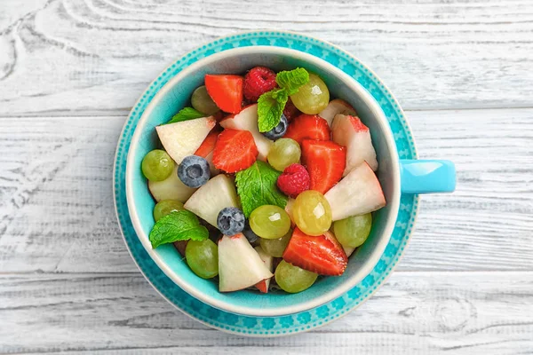 Cup with delicious fruit salad on wooden table — Stock Photo, Image