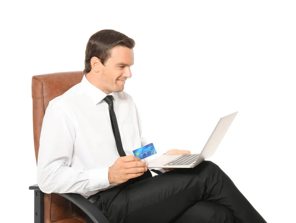Jeune homme d'affaires tenant une carte de crédit tout en utilisant un ordinateur portable sur fond blanc — Photo