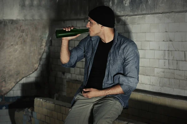 Człowiek siedzi i pije alkohol w opuszczonym budynku — Zdjęcie stockowe