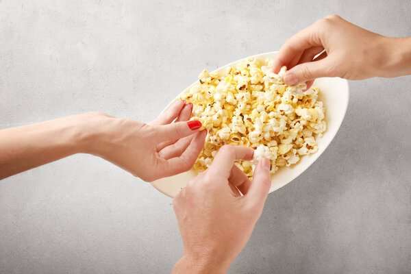 Люди берут попкорн с тарелки
