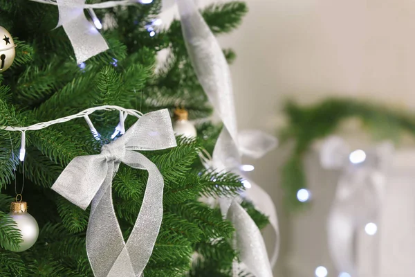 Silver ribbons and Christmas lights on fir tree — Stock Photo, Image