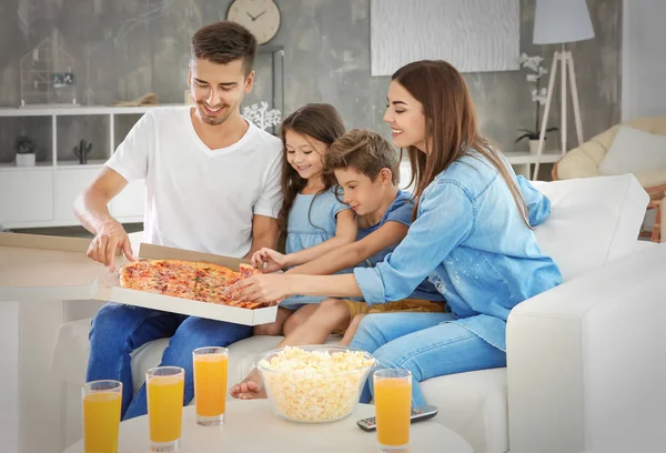 Ευτυχισμένη οικογένεια τρώει πίτσα ενώ παρακολουθείτε τηλεόραση στον καναπέ στο σπίτι — Φωτογραφία Αρχείου