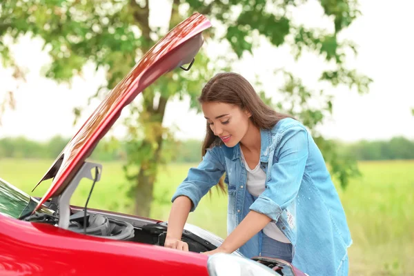 Mladá žena opravovat auto — Stock fotografie