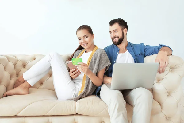 Jeune couple avec ordinateur portable et smartphone à la maison. Concept de magasinage Internet — Photo