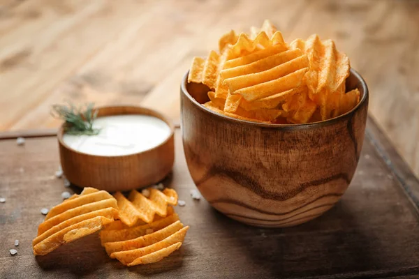 Bowls with potato chips and sour cream on wooden board — Stock Photo, Image