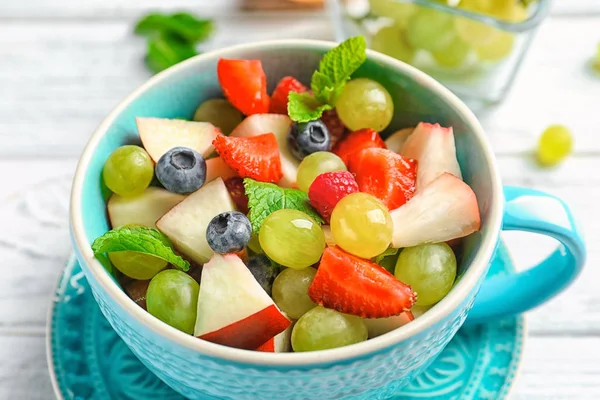 Tasse mit köstlichem Obstsalat auf Holztisch — Stockfoto