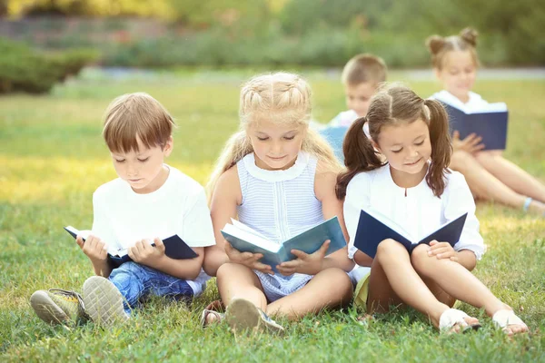 Lindos niños leyendo libros en el parque —  Fotos de Stock