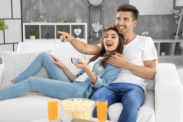 Jeune couple regarder la télévision sur le canapé à la maison — Photo