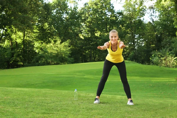 Young sporty woman doing exercise in green park — Stock Photo, Image
