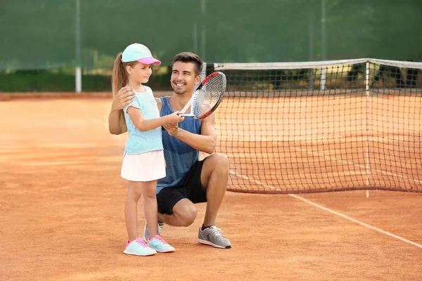 Young trainer with little girl on tennis court — Stock Photo, Image